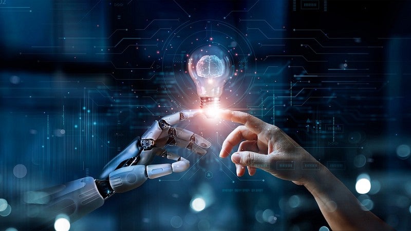 robot finger and human finger touching a lightbulb
